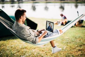 A man relaxing outside doing remote work.